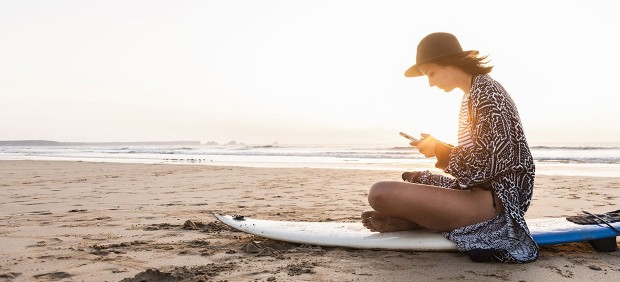 Mujer mirando el móvil en la playa